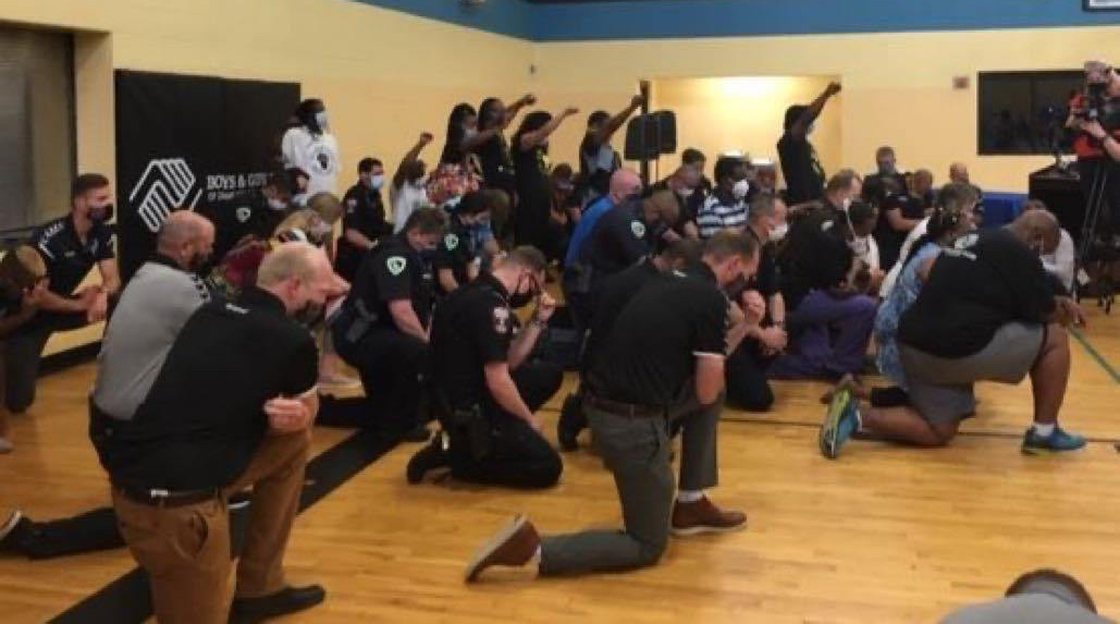 Police kneel, black power fist