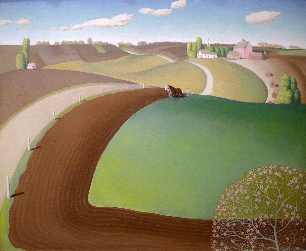 A picturesque landscape painting featuring rolling hills, a winding road, farmland, and a distant farm with a windmill. A farmer is plowing a green field with a horse, while trees and a blooming shrub are in the foreground, under a clear blue sky with fluffy clouds.